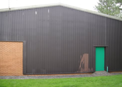 Gable end elevation of Industrial building previously coated with a Plastisol paint system. Weston Painting Contractors of Cardiff prepared all dilapidated sub-straights by brushing and sanding effected areas prior to the application of Rust-Oleum water based metal cladding primer.